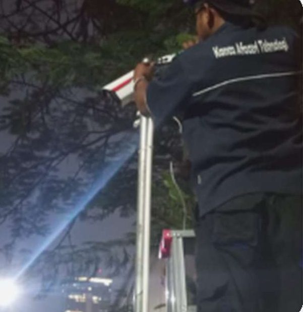Teknisi memasang kamera CCTV di malam hari